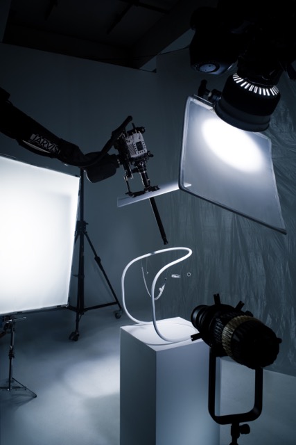 Une photo du tournage des capsules courbet produites par mat. studio montrent la structure du set design du film balais aérien, sur laquelle sont suspendus les bijoux de la collection. Deux robots motion control l'entourent : l'un avec une caméra, l'autre avec une lumière. Ils sont programmés en synchro.